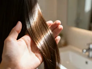 Miska z naturalnym peelingiem do skóry głowy i drewniana szczotka na marmurowym blacie w jasnej łazience.
